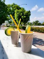 Refreshing beverage cups with lemon and lime garnishes in a sunny outdoor setting photo
