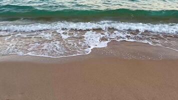 A beautiful beach scene characterized by gentle waves lapping against the warm sand, with a distant shoreline at sunset photo