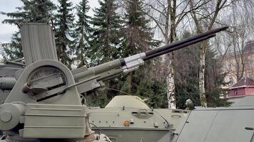 This is a closeup view of a heavy artillery gun that is mounted on a tank, showcasing intricate military engineering photo