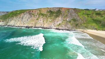 Witness the stunning aerial view showcasing the turquoise ocean waves dramatically crashing against rocky cliffs photo