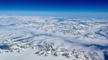 Stunning aerial footage showcases breathtaking snowcovered mountains contrasted against a bright blue sky photo