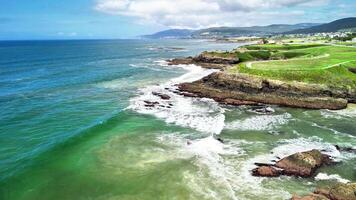 A stunning aerial view shows waves crashing on a rugged shore, highlighting vibrant ocean colors with beauty photo