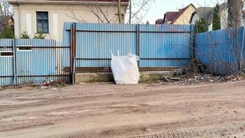 A deserted area showcasing a blue fence and a large pile of trash, which highlights urban decay and neglect photo