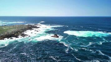 Experience breathtaking and stunning aerial views of rocky coasts and vibrant turquoise waves beneath a serene blue sky photo