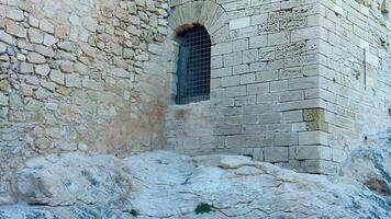 A close-up of an ancient stone building featuring a grated window, showcasing historic architecture. photo