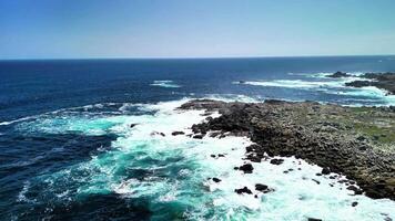 Incredible drone footage captures the stunning sight of vibrant waves dramatically crashing against rugged rocks photo