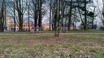 A serene and tranquil park scene that features benches, lush trees, and a hint of a building in the background photo