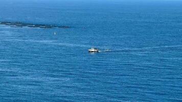 A serene view of a small boat gliding through vibrant blue waters near an aquaculture farm, showcasing nature photo