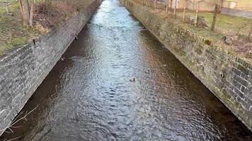 A stunning and picturesque scene of clear, serene water flowing gracefully through a charming channel with stone walls photo