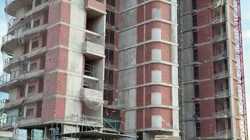 This image shows a multistory building under construction, featuring scaffolding and visible brickwork photo