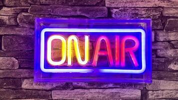 A bright neon sign that prominently says ON AIR, ideal for studios, media setups, and creative spaces photo