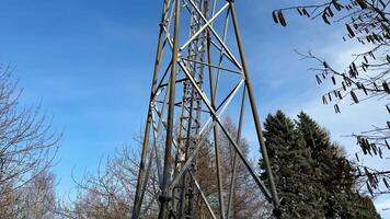 A tall and impressive communication tower is surrounded by lush green trees under a beautiful clear blue sky photo