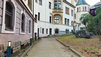Historic buildings gracefully encircle a serene courtyard featuring charming pathways and vibrant, lush greenery photo
