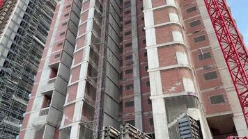 A modern, towering highrise building is currently under construction, featuring cranes and scaffolding all around photo
