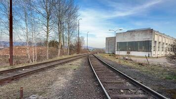 A beautifully serene view of an abandoned and overgrown railway track located next to an old industrial building photo