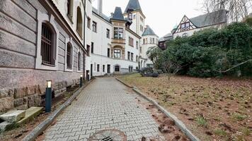 A picturesque walkway winds alongside an elegant, historic old building, embraced by the calming nature around photo