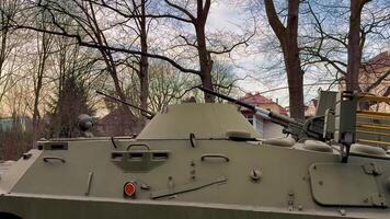 An armored vehicle is positioned among green trees, balancing nature and military might in a serene environment photo