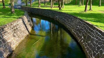 A serene and picturesque view of a winding stream gracefully flowing, surrounded by vibrant green grass and lush trees photo