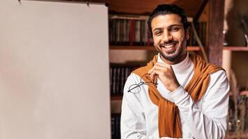 E-Learning And E-Teaching. Young Arab Male Teacher Standing Near Blackboard Teaching English Language Remotely From Home, Smiling To Camera. Distance Learning And Teaching Concept photo