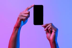 Two African American Male Hands Holding Smartphone With Black Screen Over Purple Neon Background, Unrecognizable Man Demonstating Copy Space For Website Or App Design, Mockup Image photo