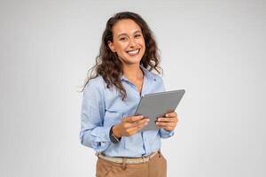 Smiling caucasian young businesswoman use tablet, app for social networks, presentation business, isolated on gray studio background. Work and chat on gadget, study online with technology photo