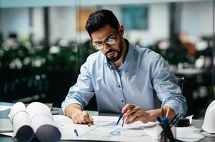 Concentrated busy handsome millennial islamic male engineer with beard in glasses, think about project in office interior, professional architect work in factory. Solving construction planning problem photo