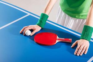 Close-up of player resting paddle and ball on table tennis surface, ready to start the match. photo