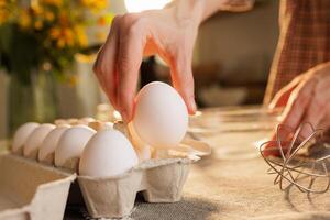 Hand Picking an Egg from a Carton in a Cozy Kitchen photo