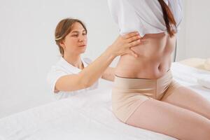 Specialist Examining Patients Lower Spine for Scoliosis, Curvature, Hernia or Postural Deformities photo