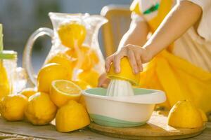 Child Squeezing Fresh Lemon Juice with Manual Juicer, Summer Citrus Drink Preparation, Healthy Lifestyle photo