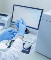 Scientist Conducting Laboratory Analysis with Glassware and Computer Data in Modern Medical Research Lab photo