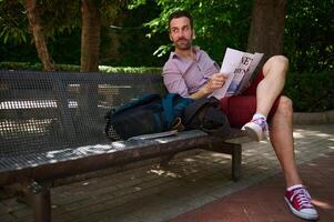 Man Enjoying Leisurely Reading on a Park Bench in a Serene Outdoor Setting photo