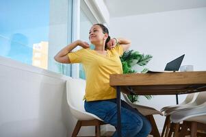 Woman Stretching With Relaxed Expression While Working at Home photo