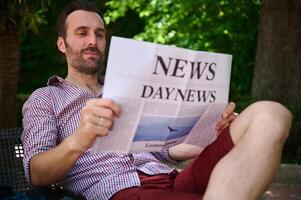 Man Relaxing Outdoors Reading a Newspaper on a Sunny Day in a Park photo