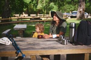 Mother and Child Enjoying Nature at a Picnic Table in a Forest Campground photo