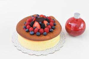 Fluffy Japanese Cheesecake topped with strawberries, raspberries, blueberries, and blackberries with bottle of red berry sauce top view of delightful and popular dessert photo