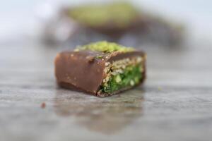 Chocolate Pistachio Bar with Wafer Layers cut in half to showcase its intricate layers with chocolate coating, thin crispy wafer layers, and green pistachio filling closeup side view of sweet treat photo