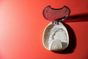 Transparent dental aligners lie in a case on a colored background. Aesthetic and comfortable correction of jaw bite. Copy space photo