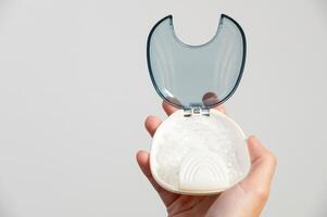 Transparent dental aligners in a case for storage and transportation are held by a woman's hand. Aesthetic and convenient correction of jaw bite. Copy space photo