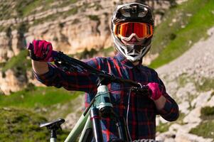 Cyclist in helmet and glasses against the backdrop of rocky sharp mountains. Extreme summer cycling in the mountains photo
