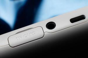 Close-up macro shot of the side panel of an electronic device, phone or portable gaming console. SD memory card slot with a protective cover and two mini-jack audio and type C connectors for charging photo