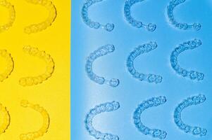 Invisible transparent brackets or parentheses on blue yellow background lie in a pattern, top view photo