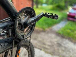 Close-up of dirty bicycle crankset and pedal with blurred background photo