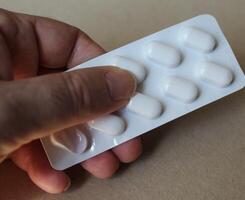 Hand holding pills in blister packs isolated photo