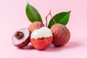 Juicy Lychee with cut in half and leaves isolated on pink background. photo