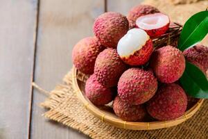 tyop view of Juicy Fresh Lychee in Bamboo Basket on Rustic Wooden Table Tropical Exotic Fruit photo