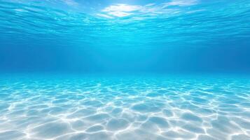 Clear blue underwater ocean scene with sunlight showing light reflections on sandy sea floor in a calm and tropical marine environment. photo