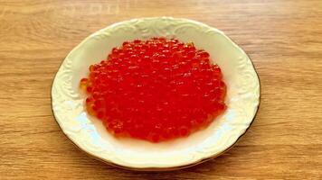 A plate with red caviar on top of a wooden table video