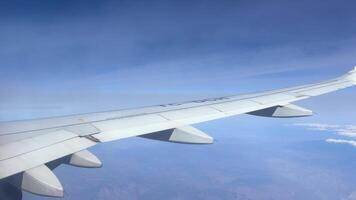 View from the window of a high flying airplane wing and thin clouds flying above it on a sunny day, travel concept video