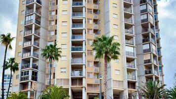 This shows a tall apartment building with palm trees, highlighting balconies and large windows, perfect for projects on urban living video